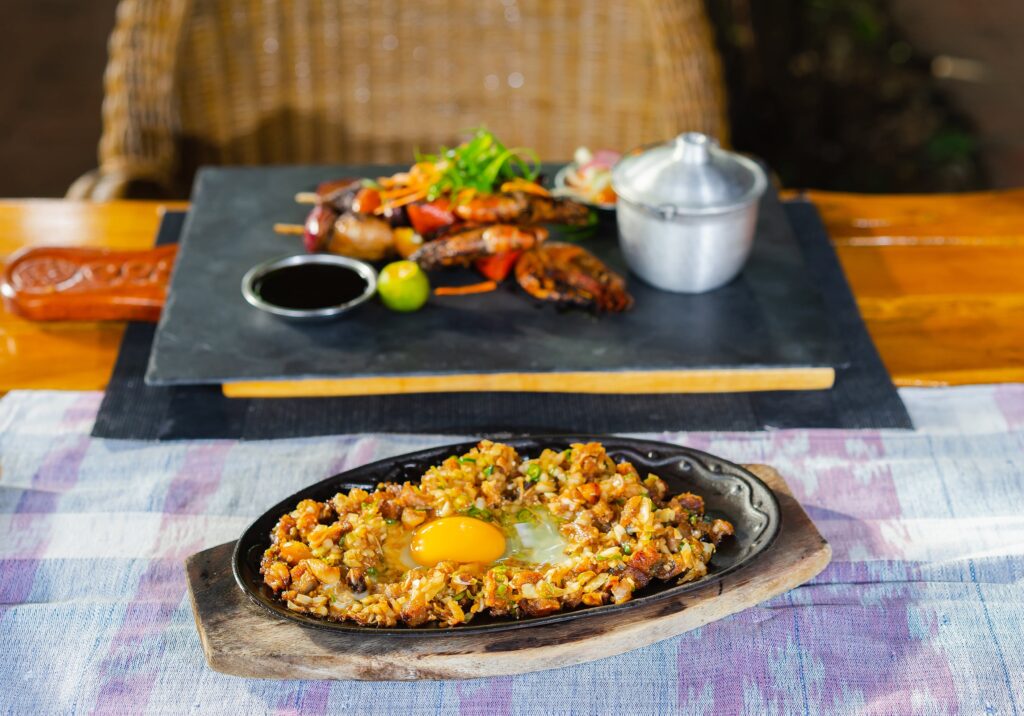 Sizzling pork sisig on the table with grilled shrimps